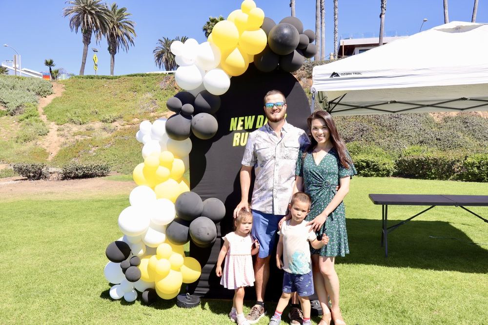 A dad, mom, and their two kids in front of the balloon-framed NDRC backdrop