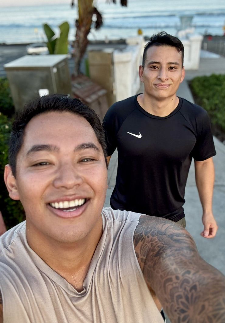 Josh smiling in a selfie with a fellow run club dad on the walk to The Strand, the ocean behind them