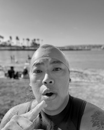 Josh in a swim cap and wetsuit on the beach after an open-water swim